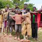 Group of children standing behind a wooden fence in a rural setting.